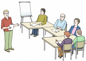 Workshopsituation: Fünf Personen sitzen in einem Semianrraum mit Flipchart an einem Tisch und hören einem Vortragenden zu